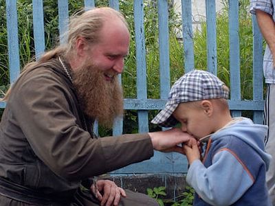 Young boy kissing the hand of an Orthodox priest.