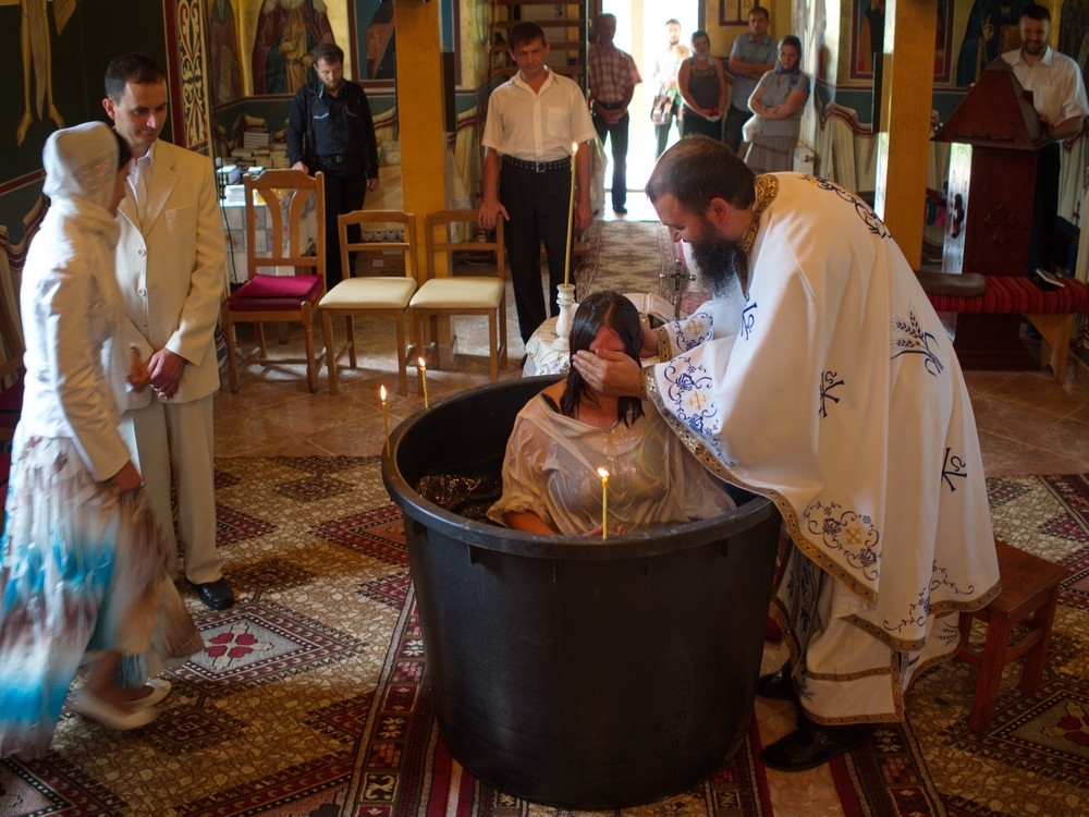 A young woman is born again through holy baptism in an Orthodox church.