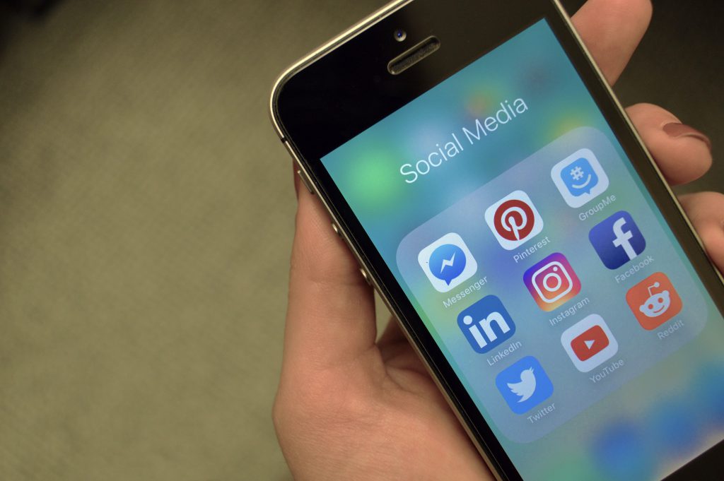 Someone holding an iPhone with social media apps on the screen