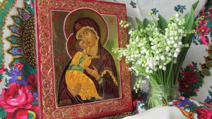 Theotokos icon on colored cloth next to flowers