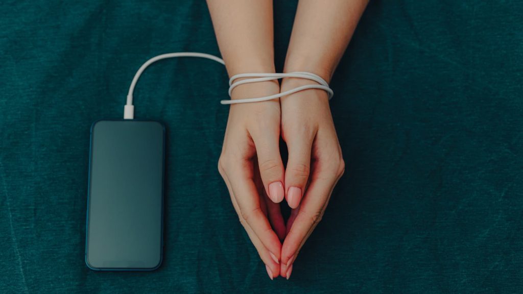 Hands beside a smartphone bound by a cable