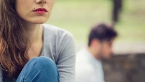 Closeup of sad woman's face with her spouse blurred in the background